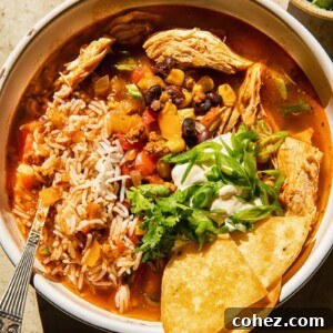 Top down view of chicken tortilla soup with rice, black beans, corn, and green onions in a vibrant bowl.