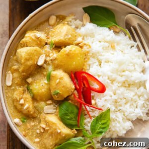 Top down shot of vibrant yellow chicken curry with rice on a plate, garnished with fresh herbs.