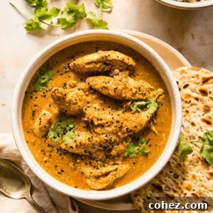 A bowl of creamy Chicken Korma, served alongside fluffy naan bread and wholesome brown basmati rice.