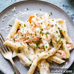 A close-up of creamy pasta beautifully tossed with delicate smoked salmon, garnished with fresh herbs.