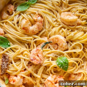 A top-down shot of linguine in a pot, generously topped with creamy 'Marry Me' shrimp sauce and vibrant basil leaves, ready to be served.