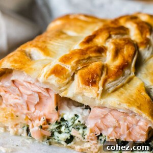 A close-up shot of an elegant Salmon en Croute, revealing the perfectly cooked salmon within its golden, flaky pastry crust.