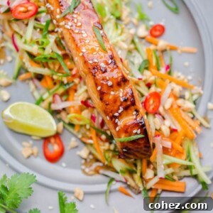 Asian glazed salmon on top of carrot and cucumber slaw with lime and chillies, creating a fresh and vibrant plate.
