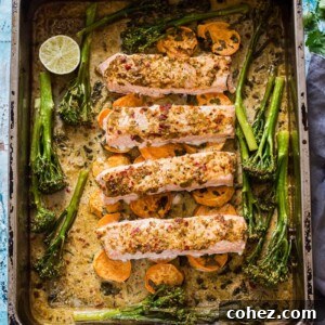 Baking tray with chili garlic salmon, sweet potatoes, and broccoli, cooked together for a convenient one-pan meal.
