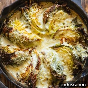Cast iron skillet with cabbage wedges arranged in a fan and covered by a creamy sauce.