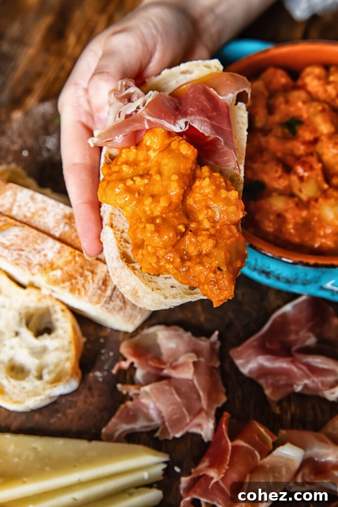A slice of crusty bread topped with a generous serving of butter beans in Romesco sauce, ready to be eaten.