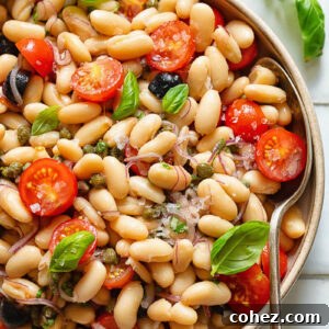 Top down shot of white bean salad in a serving bowl with basil garnish