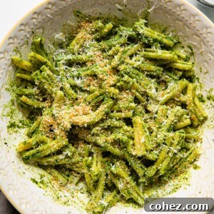 pesto pasta in a serving bowl with grated parmesan next to it