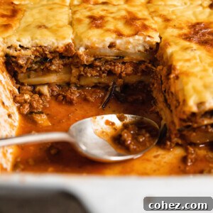 Close up shot of moussaka layers of beef and eggplant topped with creamy bechamel sauce along with a spoon