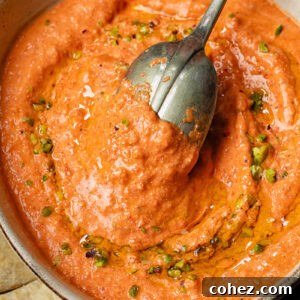 Top down shot of cottage cheese and red pepper dip in a bowl with a spoon
