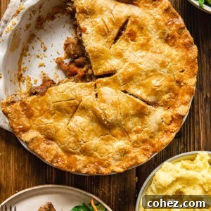 Pie with piece removed alongside salad and potatoes