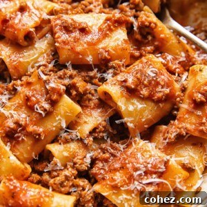 Close up shot of paccheri pasta in beef and tomato sauce with nduja and topped with Parmesan cheese