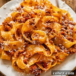 pasta with ragu sauce on a white plate and a fork