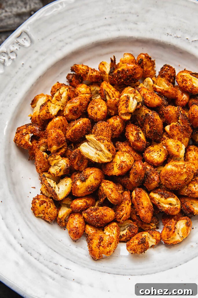 A close up image of cooked butter beans with orange spice on a rustic white plate.