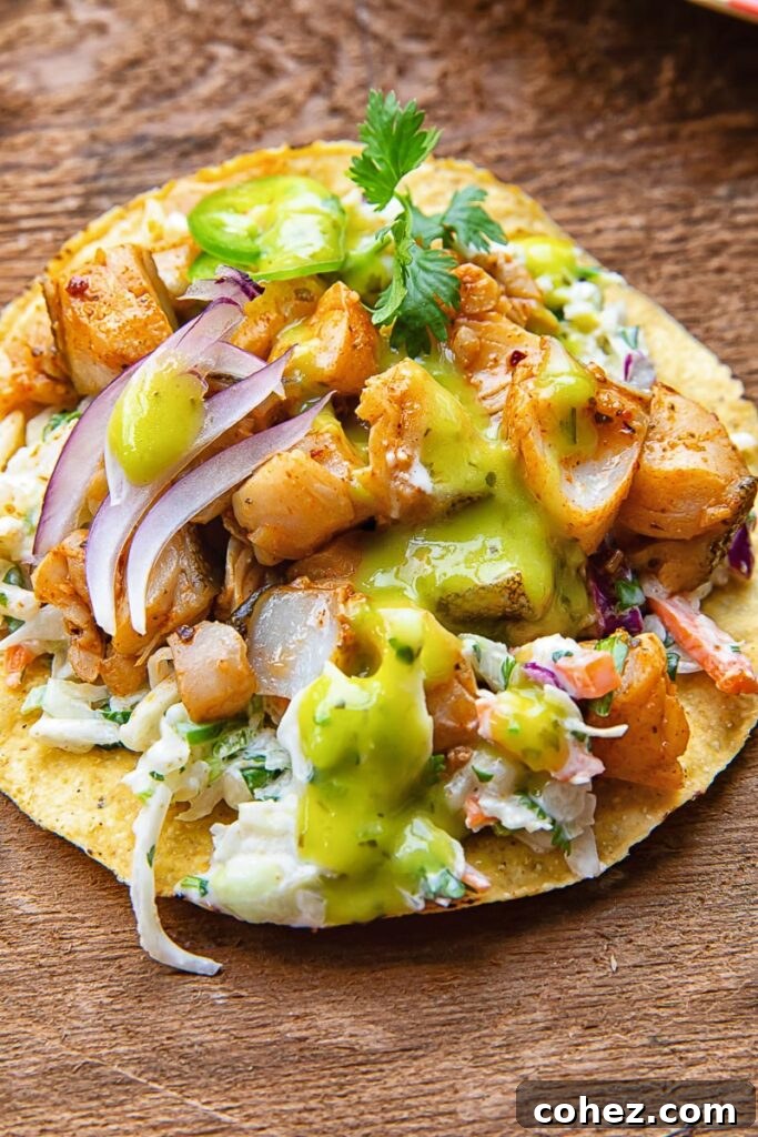 Close up of a tostada with white fish covered in salsa, coleslaw, onion slices and cilantro, on a wooden background.