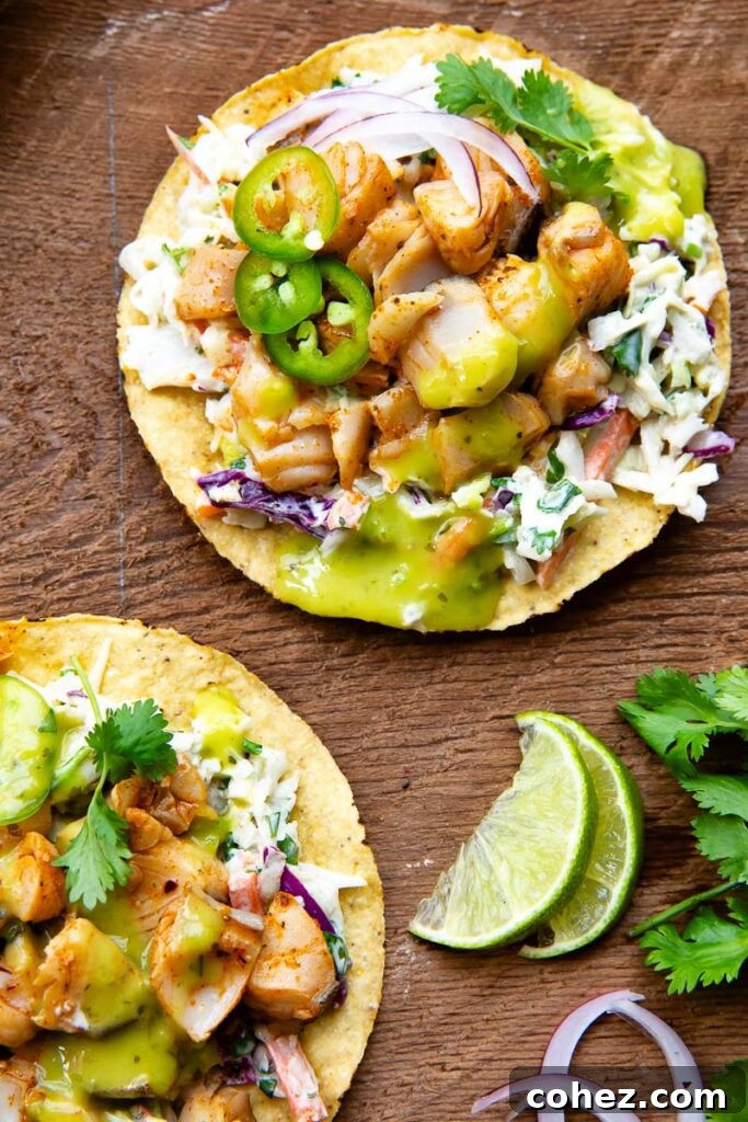 Top down view of two tostadas topped with white fish and a range of toppings on a wooden background.