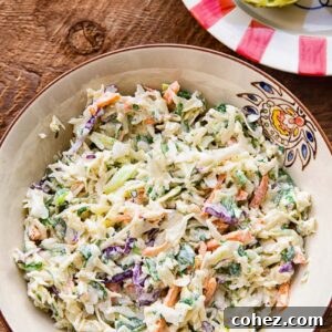Close up of slaw in a bowl on a wooden background, next to a colourful plate with a lime half.