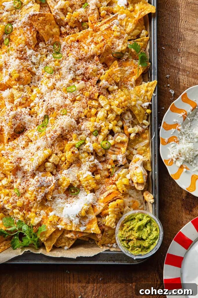 Close up of a corner of a baking sheet with nachos against a wooden background.